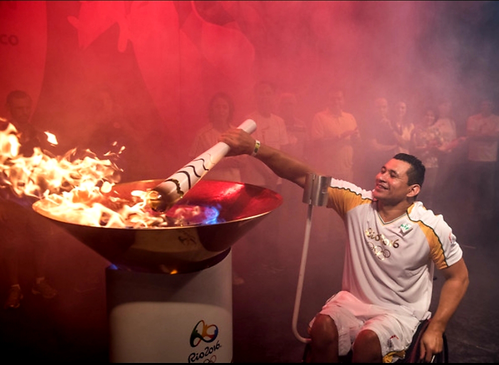 Clodoaldo sorri ao acender a pira paralímpica da Rio 2016. Pessoas assistem ao fundo.
